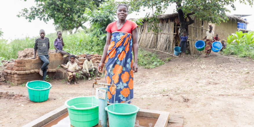 Dalesi is pictured with 2 buckets and her children in the background