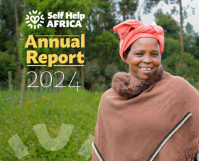 Front cover of SHA 2024 Annual Report - woman in red headscarf and a brown poncho smiling with nature background.