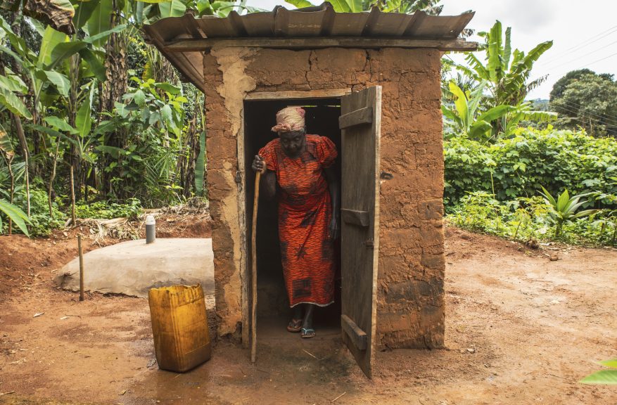 Woman at the door of an outdoor latrine shelter